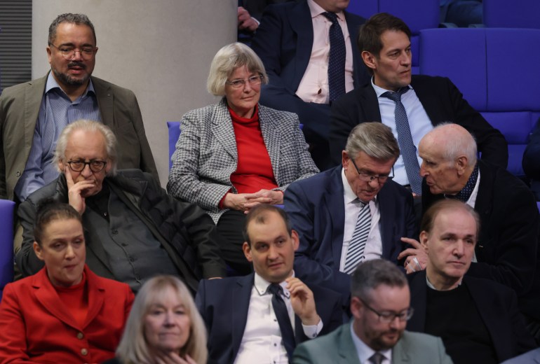 gettyimages-1942479804-1705605892 BERLIN, GERMANY - JANUARY 18: Parliamentarians of the far-right Alternative for Germany (AfD), including Gerrit Huy (C, in red sweater), whom Correctiv claims attended the November far-right meeting in Potsdam, attend a debate at the Bundestag over how to defend democracy on January 18, 2024 in Berlin, Germany. The session was called for by the coalition government members in reaction to the revelation of a secret meeting late last year between politicians and far-right extremists. According to Correctiv, the investigative group that has exposed the gathering, politicians from the far right Alternative for Germany (AfD) political party, the German Christian Democrats (CDU)-linked Werteunion, far-right extremists and financial supporters of far-right causes met at a villa in Potsdam last November. Participants at the meeting reportedly discussed how to possibly introduce legislative measures to enable the mass expulsion of immigrants from Germany, as well as German citizens with immigrant roots and German citizens who have helped refugees. News of the meeting has prompted renewed calls for banning the AfD. (Photo by Sean Gallup/Getty Images)