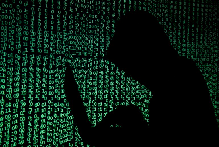 rtx35orw Hooded man holds laptop computer as cyber code is projected on him in this illustration picture