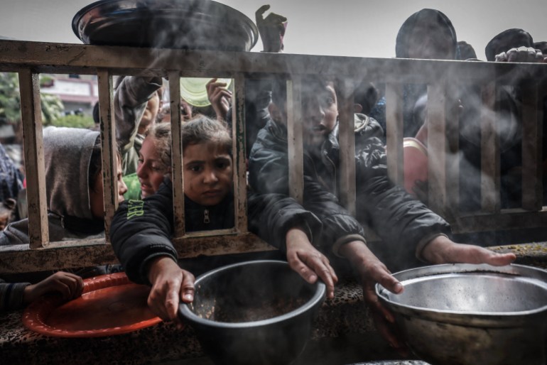 Displaced Palestinian children gather to receive food at a government school in Rafah in the southern Gaza Strip on February 19, 2024, amid the ongoing battles between Israel and the militant group Hamas. - The UN children's agency UNICEF has warned that the alarming lack of food, surging malnutrition and disease could lead to an "explosion" in child deaths in Gaza. One in six children aged under two in Gaza was acutely malnourished, it estimated on February 19. (Photo by MOHAMMED ABED / AFP)