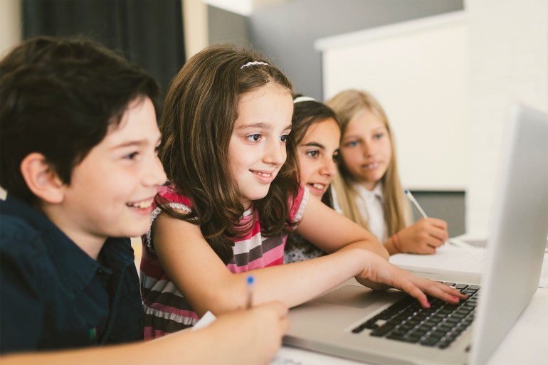 gettyimages-576757110-1691165598 Children at coding class, sitting by the desk and using laptop. They are focused on their work, finishing their assignment.