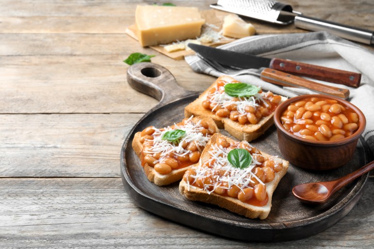 shutterstock_2032745822-1708706446 Toasts with delicious canned beans on wooden table, space for text