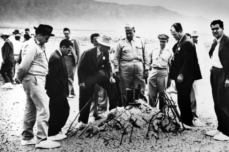 1-123 Groves and Oppenheimer Inspect Trinity Robert Oppenheimer and General Leslie Groves (center) examine the twisted wreckage that is all that remains of a hundred-foot tower, winch, and shack that held the first nuclear weapon. On the far right is Victor Weisskopf, of the Manhattan Project's Theoretical Division. | Location: Alamagordo, New Mexico, USA. (Photo by © CORBIS/Corbis via Getty Images)