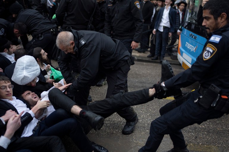 d8b3d98ad8a81-1711782766 Police officers scuffle with ultra-Orthodox Jewish men during a protest against a potential new draft law which could end their exemptions from military service in Jerusalem, March 18, 2024. (AP Photo/Leo Correa)