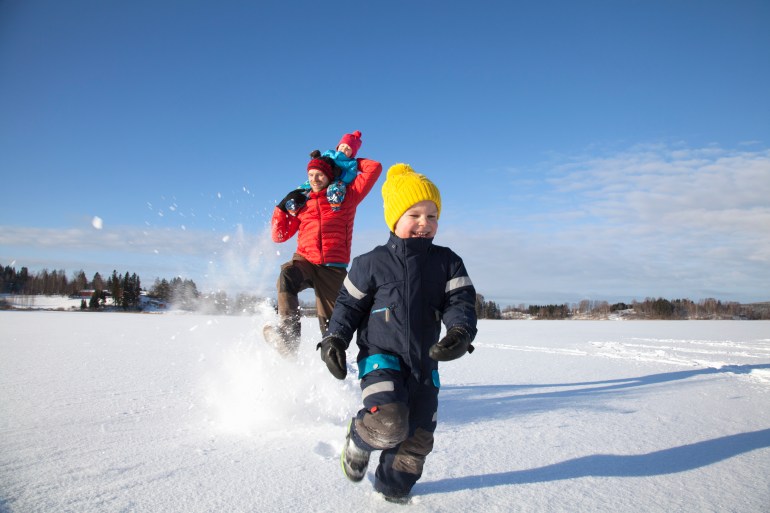gettyimages-724228111-1710929305 Father and two sons fooling around, running through snow covered landscape