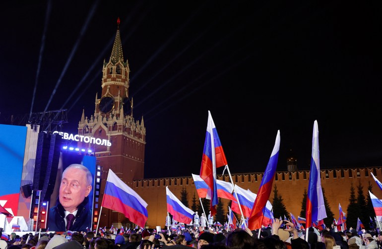 pic-661122-1710781824 Russian incumbent President Vladimir Putin, who was declared winner of the presidential election by the country's electoral commission, is seen on a screen on the stage as he attends a rally, which marks the 10th anniversary of Russia's annexation of Crimea from Ukraine, in Red Square in central Moscow, Russia, March 18, 2024. REUTERS/Maxim Shemetov
