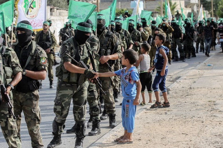 Palestinian children greet fighters from the Ezzedine al-Qassam Brigades, the armed wing of the Palestinian Hamas movement, march in the streets in the southern Gaza Strip city of Khan Yunis on July 20, 2017. (Photo by SAID KHATIB / AFP)