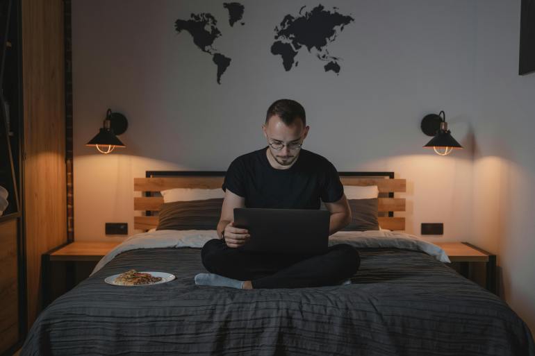 d9a4d9a5d9a4d9a52-1719331624 A Man Using a Laptop while Sitting on a Bed