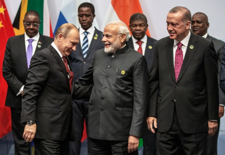 (LtoR) Russia's President Vladimir Putin, India's Prime Minister Narendra Modi and Turkey's President Recep Tayyip Erdogan greet each other as they arrive to pose for a group photo during the 10th BRICS summit (acronym for the grouping of the world's leading emerging economies, namely Brazil, Russia, India, China and South Africa) on July 27, 2018 in Johannesburg, South Africa. (Photo by Gianluigi GUERCIA / POOL / AFP)