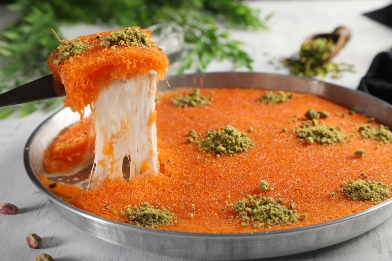 ss2067317525-1719681023 Arabic traditional kunafa. desserts rough konafa in tray sweet with pistachio and pine on top. close up
