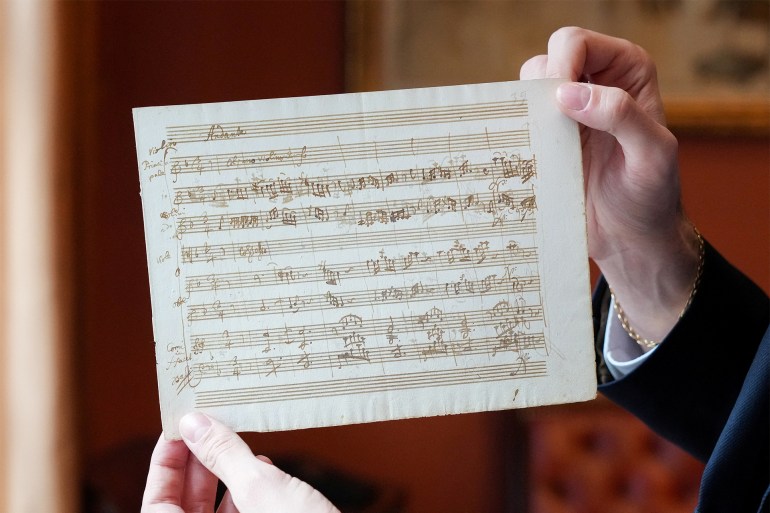 173-1720346439 A person holds a rare autograph music manuscript by Wolfgang Amadeus Mozart, رويترز