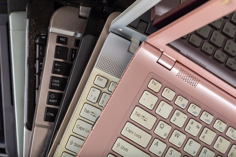 77777-4-1691665512 Stack of used laptops in different colors and models. Tha notebooks for repair and service.