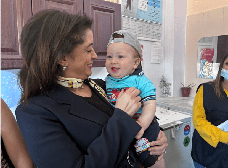 d8a7d984d8b5d988d8b1d8a9-2-24-1719817622 المديرة الإقليمية لمنظمة الصحة العالمية، الدكتورة حنان بلخي، تحمل طفلاً في مركز وادي الذهب للرعاية الصحية الأولية في حمص بسوريا (منظمة الصحة العالمية)