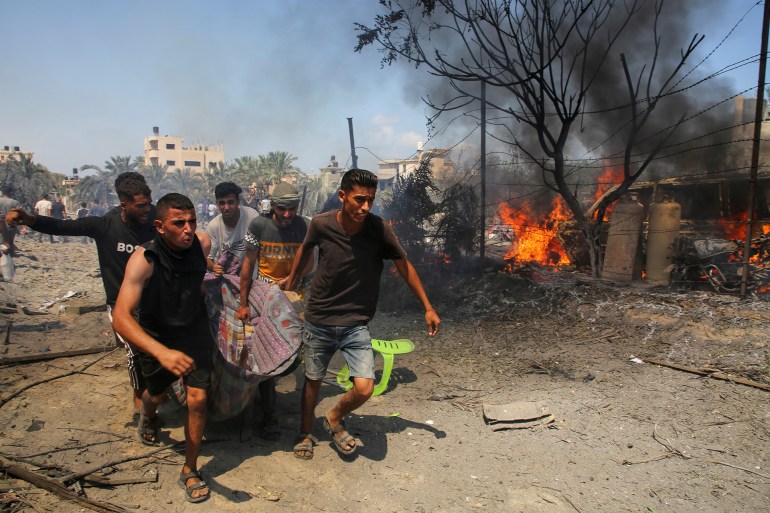 People carry a casualty at the site of what Palestinians say was an Israeli strike at a tent camp in Al-Mawasi area, amid Israel-Hamas conflict, in Khan Younis in the southern Gaza Strip July 13, 2024. REUTERS/Hatem Khaled