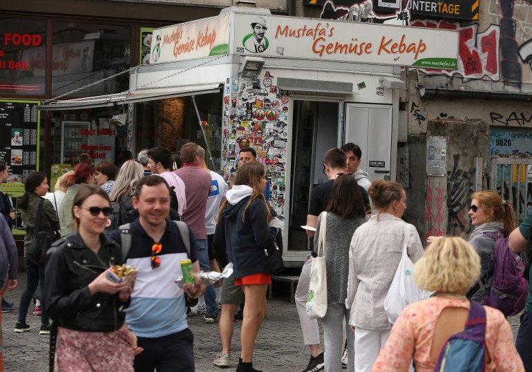 1407116387-1723120009 BERLIN, GERMANY - JULY 06: Visitors stand in line to order at Mustafas Gemüse Kebap on July 06, 2022 in Berlin, Germany. The döner kebab, a fast food sandwich made of stacked, seasoned meat turned on a rotisserie, was popularized in Germany in the early 1970s by Turkish guest workers (Gastarbeiter in German, or migrants arriving in Germany after World War II to counter labor shortages), with more stands offering the dish in Berlin than in Istanbul, and many considering it to be Germany's national dish. (Photo by Adam Berry/Getty Images)