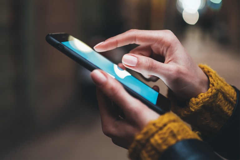 1674345967-copy point finger on screen mobile phone closeup, person texting text message, hipster touch blue screen on smartphone light night city, girls using in hands cellphone close up, online internet