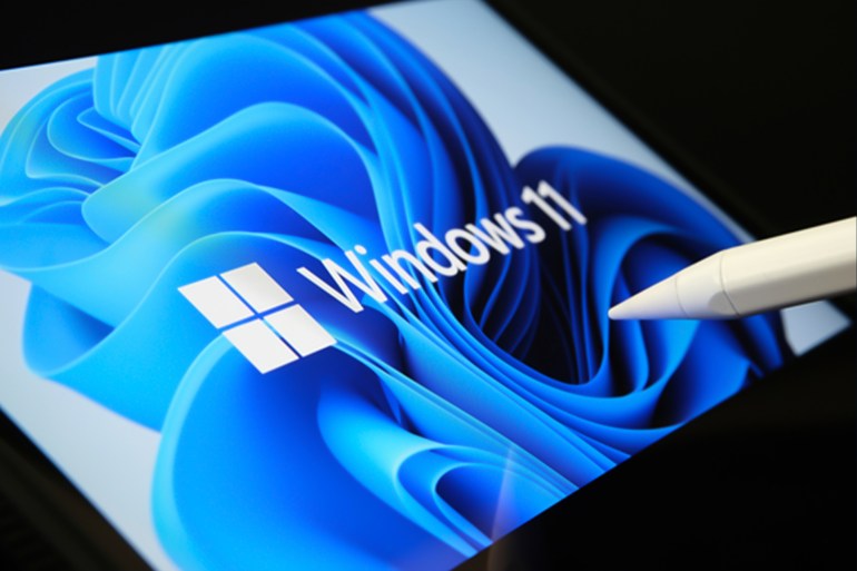 205-1723363149 Stafford, United Kingdom - July 1, 2021: Microsoft Windows 11 operating system logo seen on the screen of tablet and user pointing at it with stylus شترستوك