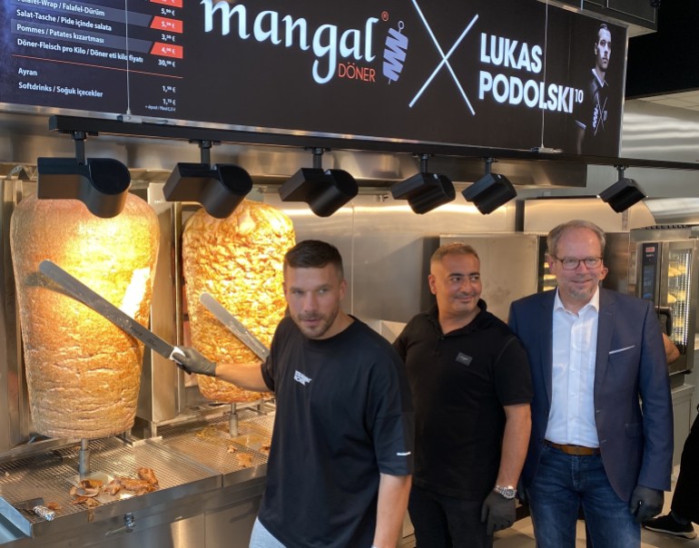 24959290-1723120986 German footballer Lukas Podolski opens the 11th branch of his chain Doner Kebab restaurant in Cologne- - COLOGNE, GERMANY - JUNE 30: German footballer Lukas Podolski (L), who plays as a forward for Turkish team Antalyaspor, poses for a photo with a doner knife with his Turkish co-partner Metin Dag (2nd L) as they open up the 11th branch of their chain Doner Kebab restaurant named "Mangal Doner" in Bergheim town of Cologne, Germany on June 30, 2021. Bergheim Mayor Volker Miesseler (R) also attended the opening of the restaurant.