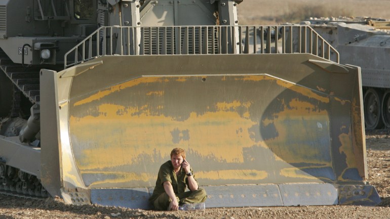 An Israeli soldier speaks on a cell phone in front an army bulldozer on the field near the kibbutz of Mefalsim, just outside the Gaza Strip. An Israeli soldier speaks on a cell phone in front an army bulldozer on the field near the kibbutz of Mefalsim, just outside the Gaza Strip, July 17, 2005. Israel's cabinet will probably hold off a threatened offensive in the occupied Gaza Strip after security chiefs noted efforts by the Palestinian Authority to rein in militants, political sources said on Sunday. REUTERS/Oleg Popov