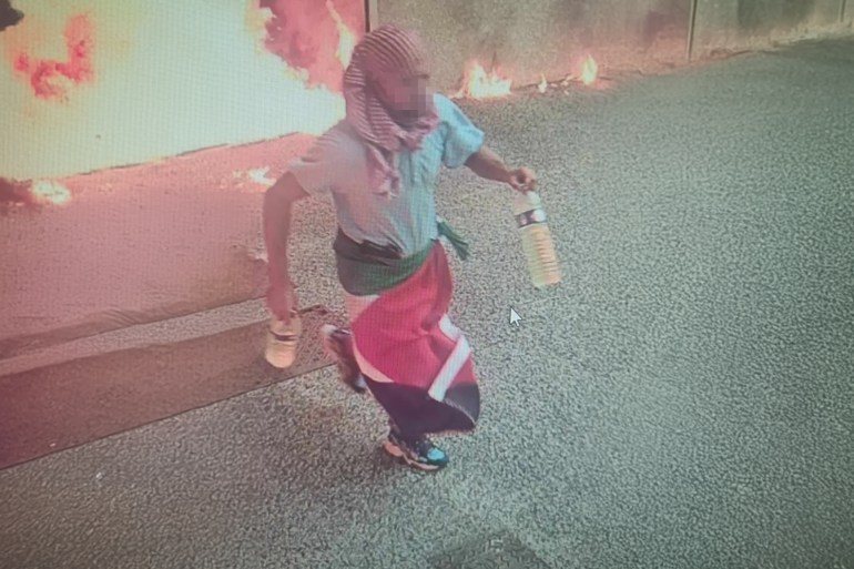 This CCTV image obtained by AFP on August 24, 2024 shows a potential suspect carrying two empty bottles and a Palestinian flag draped around his waist, leaving the scene where two cars outside the synagogue burst into flames after a gas canister likely exploded, in La Grande-Motte, southern France. An explosion outside a synagogue in southern France wounded a police officer early on August 24, 2024, in what authorities said was being treated as a potential terror attack. Security around Jewish sites was tightened following the early Saturday blast outside the Beth Yaacov synagogue in the seaside resort of La Grande Motte, near the city of Montpellier. - RESTRICTED TO EDITORIAL USE - NO MARKETING NO ADVERTISING CAMPAIGNS - DISTRIBUTED AS A SERVICE TO CLIENTS (Photo by - / AFP) / RESTRICTED TO EDITORIAL USE - NO MARKETING NO ADVERTISING CAMPAIGNS - DISTRIBUTED AS A SERVICE TO CLIENTS