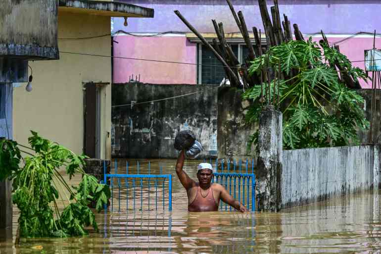A man carrying his belongings wades through flood waters in Feni, in south-eastern Bangladesh, on August 23, 2024. Flash floods wrought havoc in Bangladesh on August 23 as the country recovers from weeks of political upheaval, with the death toll rising to 13 and millions more caught in the deluge. (Photo by MUNIR UZ ZAMAN / AFP)