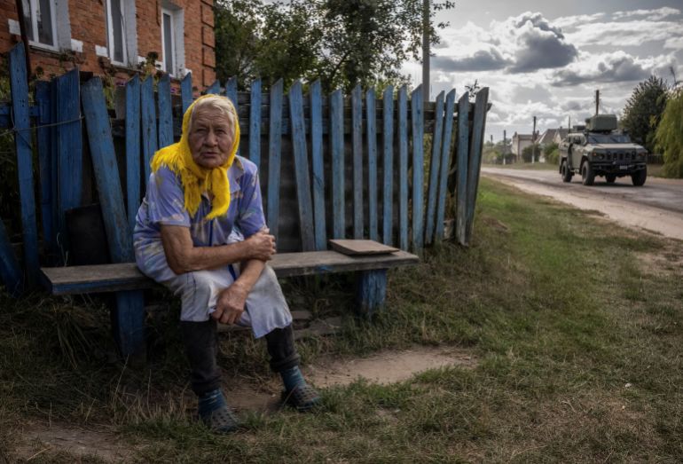 rc2dg9a5557v-1723810440 A local resident Maria sits near her building as nearby Ukrainian servicemen ride a military vehicle near the Russian border in Sumy regionA local resident Maria, 88, sits near her building, as nearby Ukrainian servicemen ride a military vehicle, amid Russia's attack on Ukraine, near the Russian border in Sumy region, Ukraine August 15, 2024. REUTERS/Viacheslav Ratynskyi DATE 15/08/2024 SIZE 3500 x 2375 Country Ukraine SOURCE