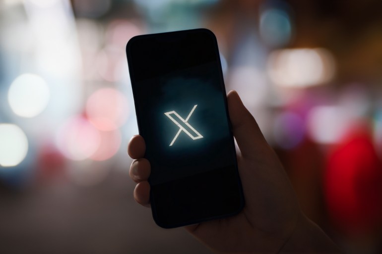 shutterstock_2336316901-1697643969 Man hand holding Phone with social networking service x logo on the screen, Twitter will officially rebrand as X later today, Elon Musk confirms.