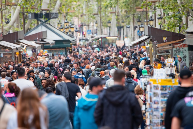 shutterstock_2457776039-1723039763 Barcelona, Spain - April 27 2024: Crowds of tourists walking on La Rambla street in Barcelona, Spain