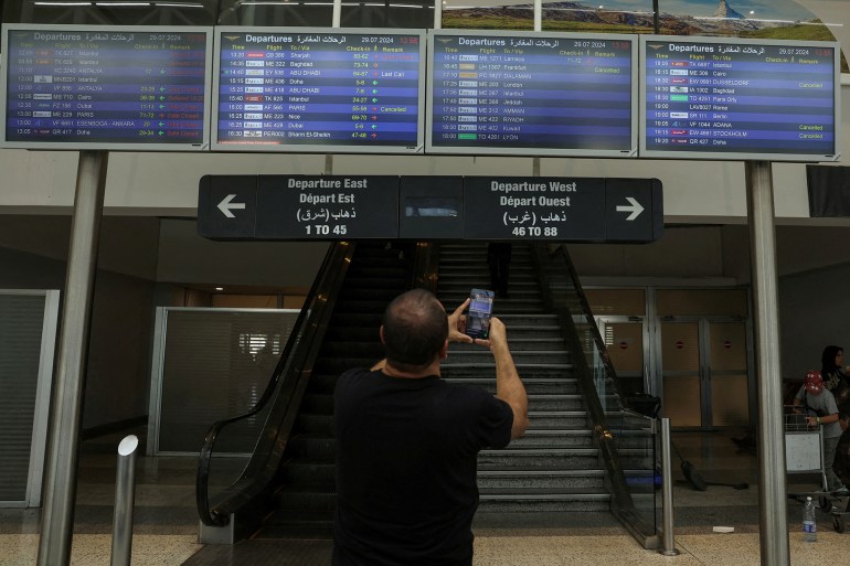 A man takes a picture of flight information boards at the Beirut–Rafic Hariri International Airport, in Beirut, Lebanon July 29, 2024. REUTERS/Emilie Madi