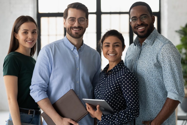 work1-1727361973 Group portrait of happy multiethnic united millennial team in modern office. Successful employees standing together, meeting in workspace, looking at camera and smiling Team work concept. Head shot; Shutterstock ID 2310800821; purchase_order: aljazeera ; job: ; client: ; other: