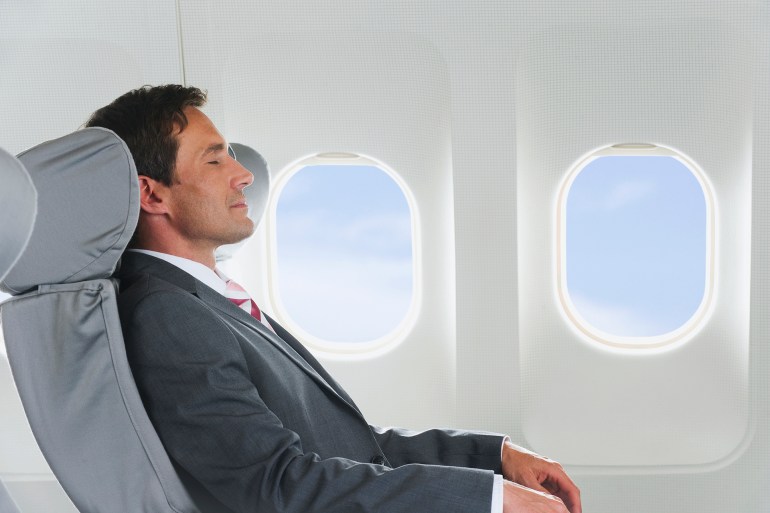 gettyimages-135383778-1728072627 Germany, Bavaria, Munich, Mid adult businessman relaxing in business class airplane cabin - stock photo