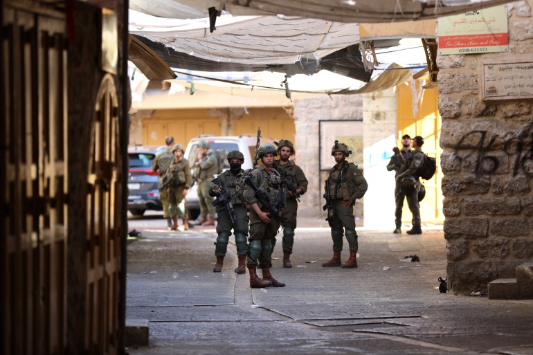 HEBRON, WEST BANK - AUGUST 17: A group of Jewish settlers under the protection of Israeli soldiers raids the Old City area of Hebron, West Bank on August 17, 2024. (Photo by Wisam Hashlamoun/Anadolu via Getty Images)
