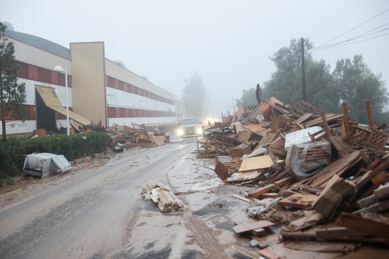 reuters-23e4-1730280612 A car drives past damaged items from a furniture factory affected by torrential rains that caused flooding in La Alcudia, Valencia region, Spain, October 30, 2024. REUTERS/Eva Manez
