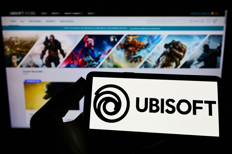 STUTTGART, GERMANY - Jan 07, 2022: Person holding cellphone with logo of French video game company Ubisoft Entertainment SA on screen in front of web page Focus on phone display ; Shutterstock ID 2117282858; purchase_order: aj; job: ; client: ; other: