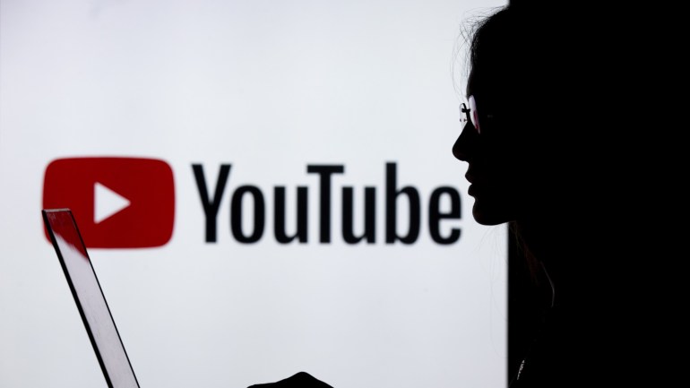 324888c9-03f5-406d-bf32-baa15159b388 Digital Applications- - ANKARA, TURKEY - JULY 18 : A silhouette of a woman with a laptop is seen in front of the logo of Youtube application in Ankara, Turkey on July 18, 2018.