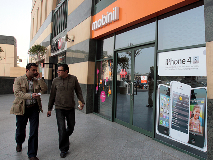 epa03194301 (FILE) A file photograph dated 15 February 2012, shows two Egyptians walking past a Mobinil mobile store in Cairo, Egypt. According to media reports on 23 April 2012, Egypt's Financial Supervisor Authorities (EFSA) authorizes France Telecom to make an offer for a stake in mobile operator Mobinil. France Telecom has engaged discussions with Orascom Telecom Media and Technology Holding to buy the majority of shares in their Egyptian mobile operator Mobinil, for about 12 billion Egyptian pounds (1.5 billion euros). EPA/KHALED ELFIQI