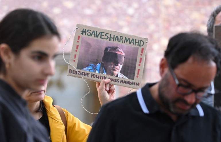 864508-01-02-1730827948 (FILES) A demonstrator holds a picture of Iranian-German Jamshid Sharmahd, who has been sentenced to death in Iran, with the lettering 'Save Sharmahd' and 'German politics has to act' during a demonstration for his release in front of the German Foreign Ministry in Berlin on July 31, 2023. Iran on October 28, 2024 executed 69-year-old German-Iranian Jamshid Sharmahd after years in captivity, media in the Islamic Republic said, sparking outrage in Germany and beyond. Berlin called the execution a "scandal" and warned of "serious consequences" for Iran's "inhumane regime", while a Norway-based human rights group labelled the execution the "extrajudicial killing of a hostage". Sharmahd, a German citizen of Iranian descent and a US resident, was seized by Iranian authorities in 2020 while travelling through the United Arab Emirates, according to his family. (Photo by INA FASSBENDER / AFP)