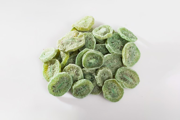 Pile of natural freeze-dried kiwifruit slices on white background. Concept of healthy and diet food