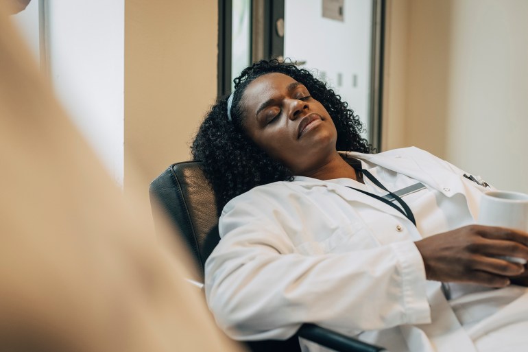 gettyimages-1461606807-1731435926 Tired female doctor taking nap during coffee break in hospital - stock photo