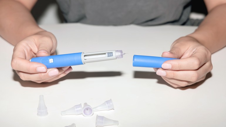 Insulin injection pen or insulin cartridge pen for diabetics. Medical equipment for diabetes parients. Woman holding an injection pen for diabetic.