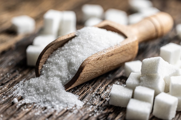 gettyimages-2157434305-1731342716 Granulated sugar in a wooden scoop or bowl on an old oak table.