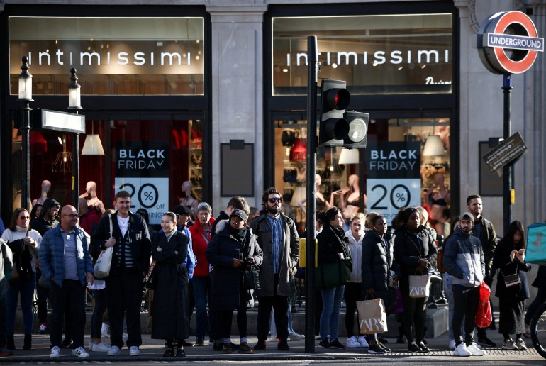 picture-11149-1732375487 FILE PHOTO: People stand near Black Friday signage in shop windows during Black Friday on Oxford Street in London, Britain, November 25, 2022. REUTERS/Henry Nicholls/File Photo