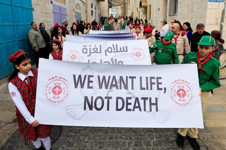 christmas-bethlehem2-1735052177 Scouts hold placards ahead of the arrival of Latin Patriarch of Jerusalem, Pierbattista Pizzaballa to attend Christmas events, near the Church of Nativity in the Old City of Bethlehem, in the Israeli-occupied West Bank, December 24, 2024. REUTERS/Mussa Qawasma TPX IMAGES OF THE DAY