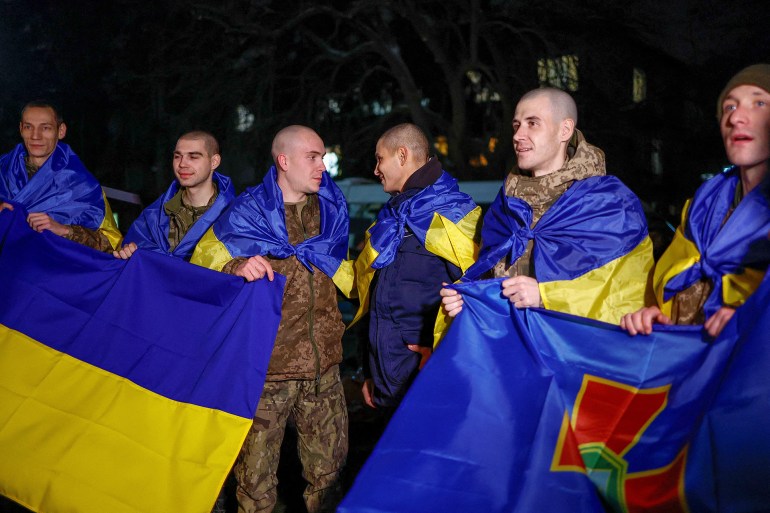 d8a7d988d983d8b1d988d8b3-d8b1d988d98ad8aad8b1d8b23-1735581567 Ukrainian prisoners of war (POWs) wrapped with national flags return after a swap, amid Russia's attack on Ukraine, in an undisclosed location in Ukraine, December 30, 2024. REUTERS/Valentyn Ogirenko