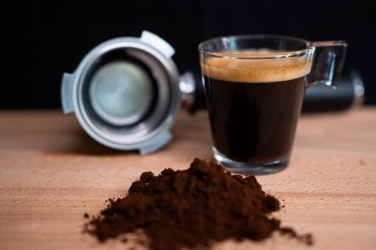 gettyimages-1947915732-1734446175 A glass of espresso coffee, a portafilter, and some espresso coffee blend are sitting on a wooden surface. (Photo by Nikos Pekiaridis/NurPhoto via Getty Images)