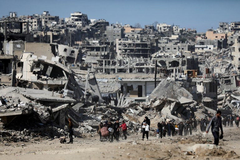 Palestinians make their way past the rubble of destroyed houses and buildings, following a ceasefire between Israel and Hamas, in Jabalia in the northern Gaza Strip, January 21, 2025. REUTERS/Dawoud Abu Alkas