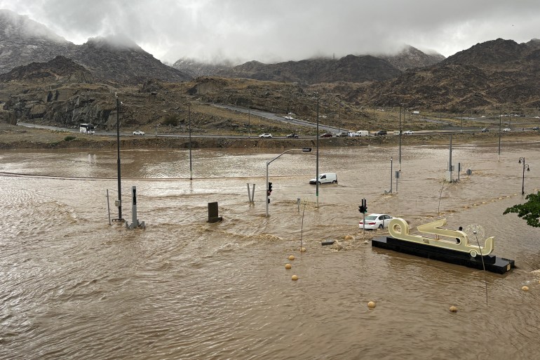d8a8d98a-1-1736496388 Commuters make their way through a flooded road after heavy rains in Mecca on January 6, 2025. (Photo by AFP)