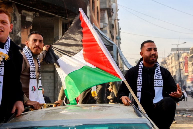 Men ride in a car adorned with a Palestinian flag along a street in Gaza City on January 19, 2025, following the ceasefire deal in the Israel-Hamas war. A long-awaited ceasefire in the Israel-Hamas war was delayed January 19 after Prime Minister Benjamin Netanyahu said at the last minute that it would not take effect until the Palestinian militant group provided a list of the hostages to be released. (Photo by Omar AL-QATTAA / AFP)