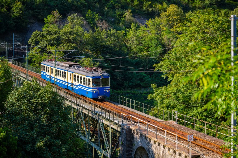 italy4-1737986244 Historic electric train on famous steel bridge in Intragna in Centovalli valley. Famous narrow gauge railway line from Locarno to Domodossola in Italy in the Swiss Alps. Popular tourist train journey.; Shutterstock ID 2335373327; purchase_order: aljazeera ; job: ; client: ; other:Historic electric train on famous steel bridge in Intragna in Centovalli valley. Famous narrow gauge railway line from Locarno to Domodossola in Italy in the Swiss Alps. Popular tourist train journey.; Shutterstock ID 2335373327; purchase_order: aljazeera ; job: ; client: ; other: