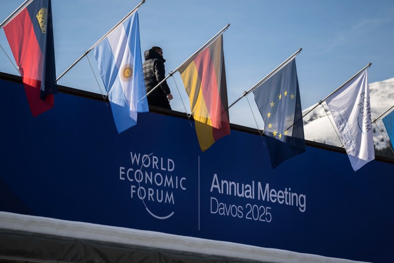sfvsdfvsd4-1737372001 A staff walks to fix flags placed atop the Congress Center during the World Economic Forum (WEF) annual meeting in the Alpine resort of Davos on January 20, 2025. (Photo by Fabrice COFFRINI / AFP)