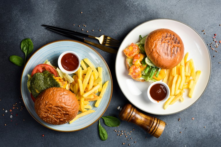 shutterstock_2477073125-1729513713 A set of burgers and fries. In plates. On a stone table. Top view.; Shutterstock ID 2477073125; purchase_order: AJ; job: ; client: ; other: